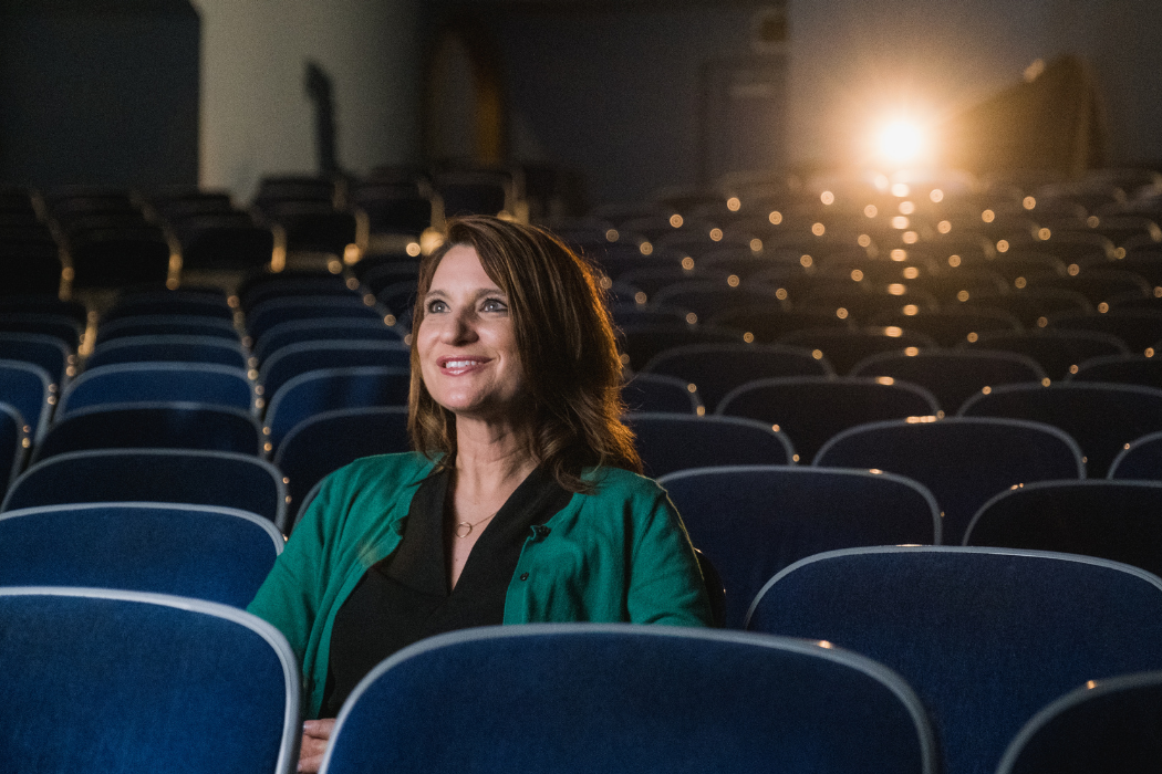 woman sitting in an empty theater with a spotlight behind her