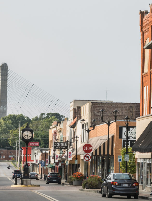A street-level view of main street businesses in downtown Cape Girardeau with the Bill Emerson Memorial Bridge in the background.