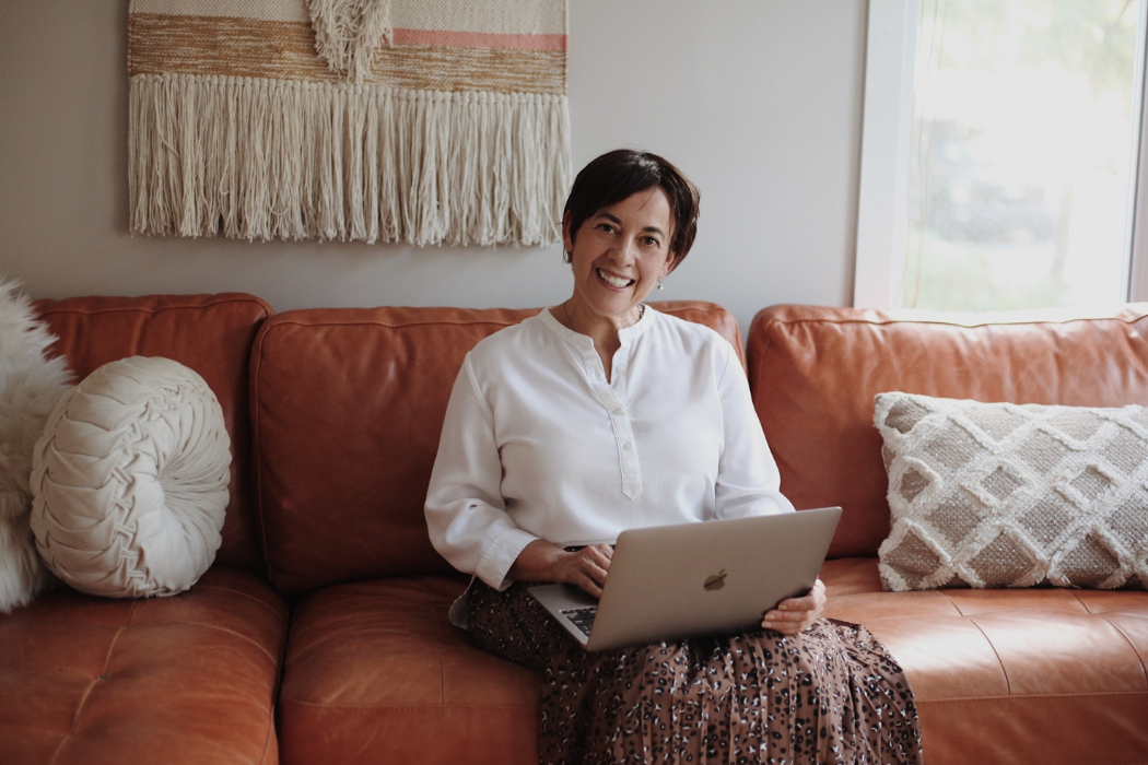 Person sitting on a leather couch working on their laptop