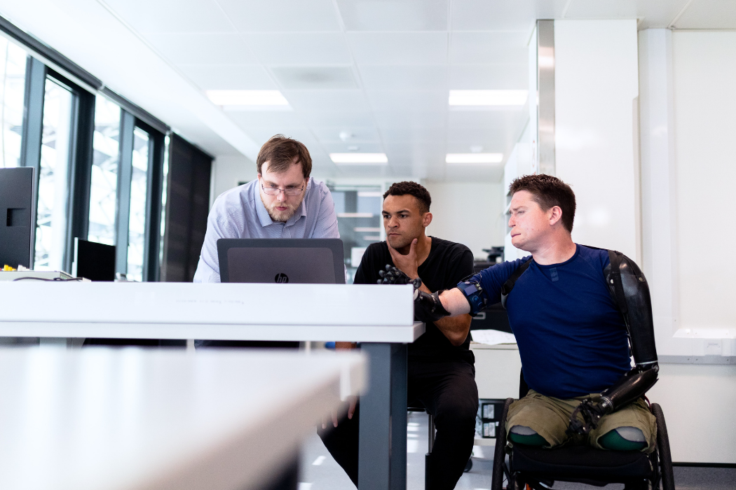 Three people working around a computer