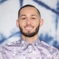 Brett Ellis headshot in front of a patterned background.
