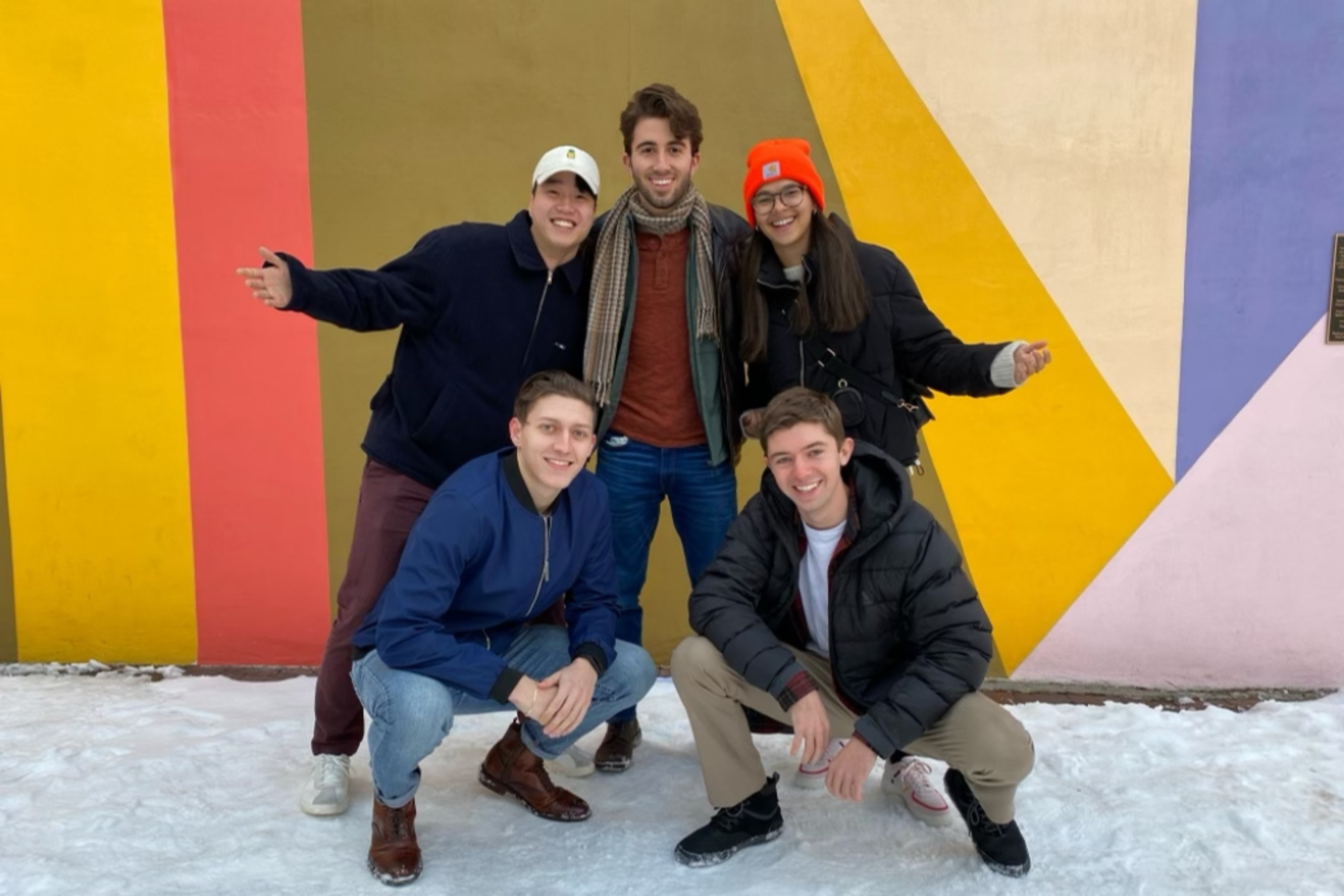 Group of people posing outside in front of a colorful wall