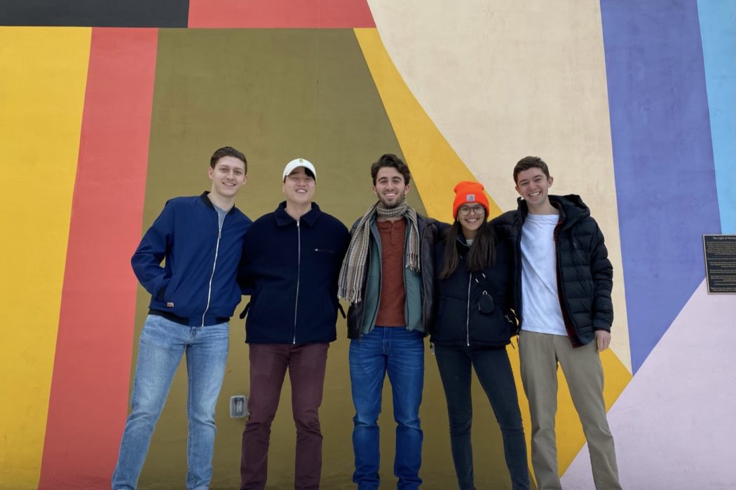 group of people standing in front brightly colored wall