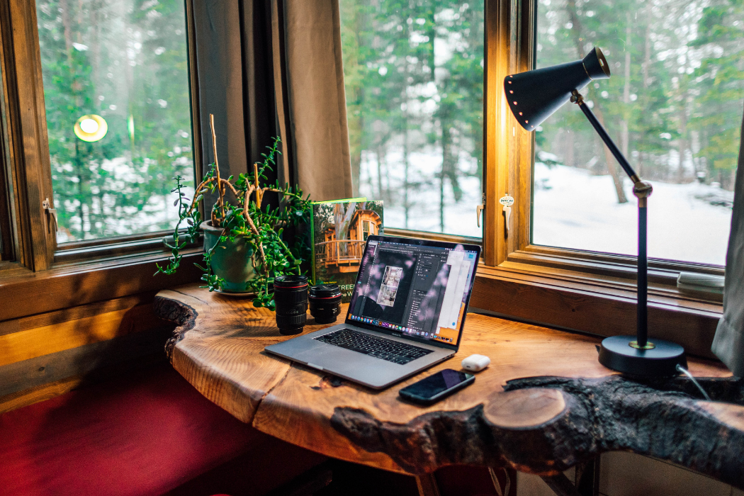 Desk in a corner with a light and a view of snow and trees