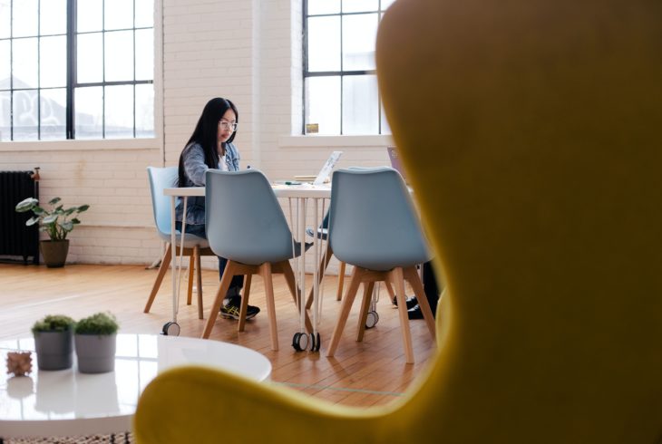 Person sitting across a room working on a laptop