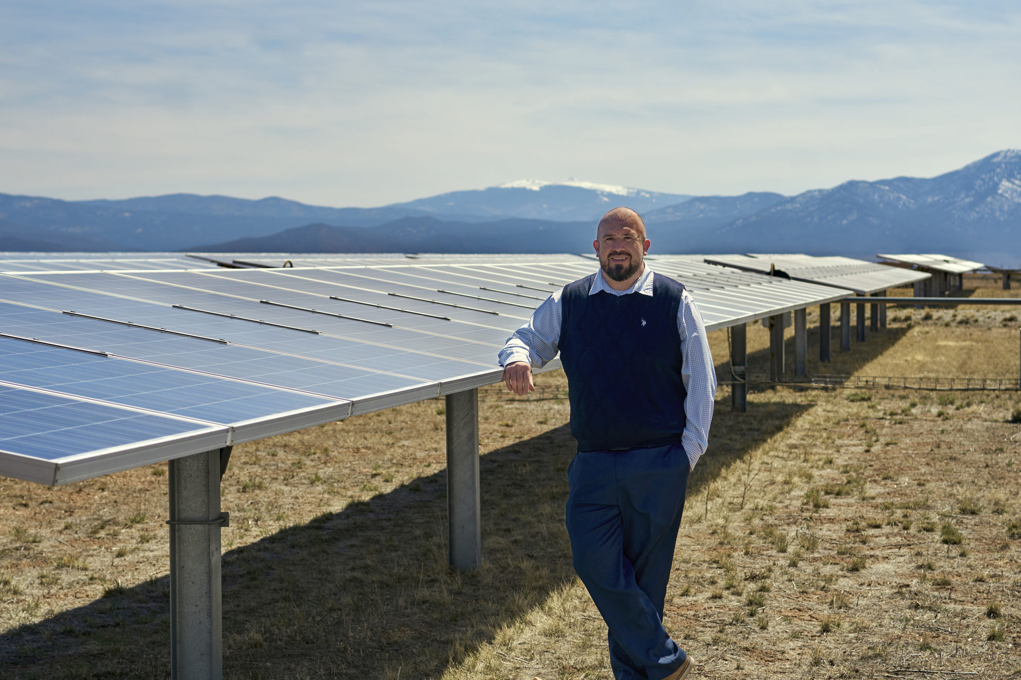 Daniel Trujillo leans against solar panels in Taos