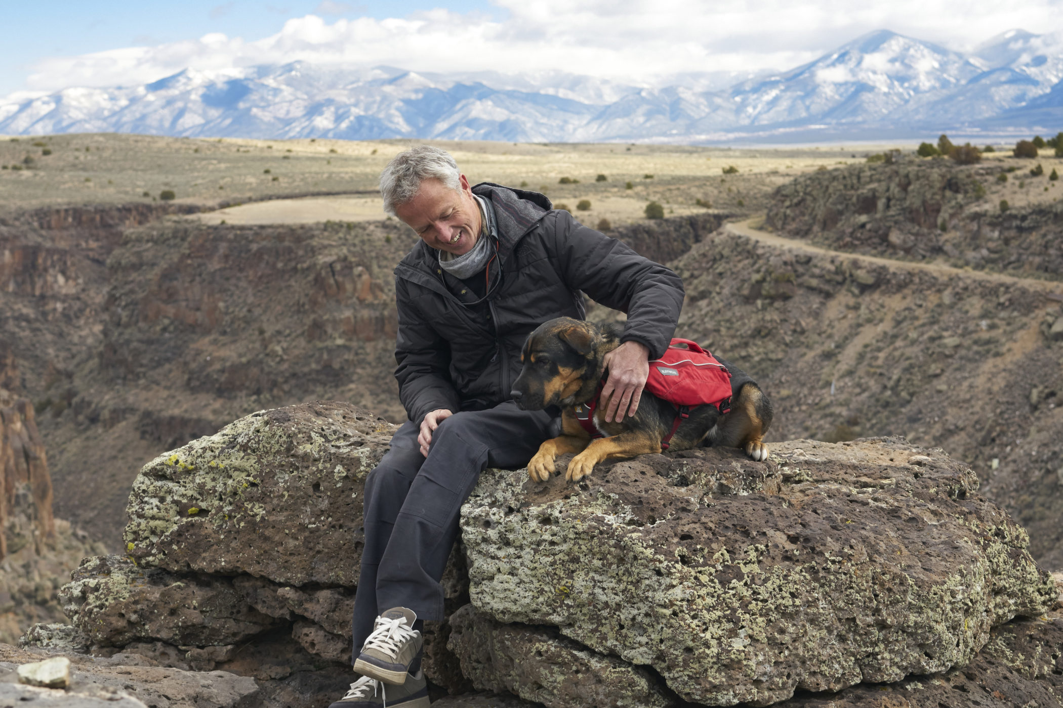 Peter Walker pets his dog near a canyon