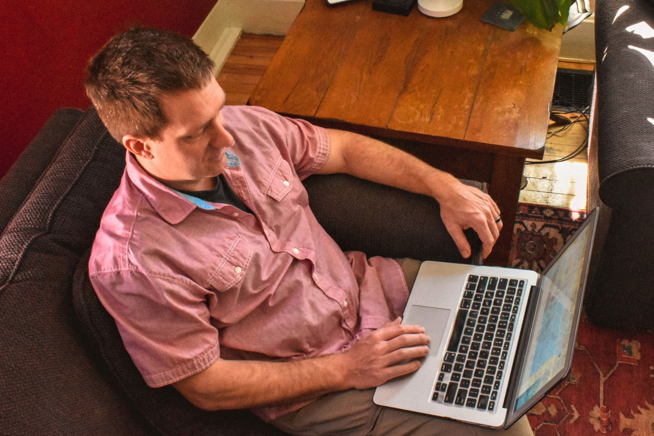 TJ Whipple sits on a couch working on his laptop