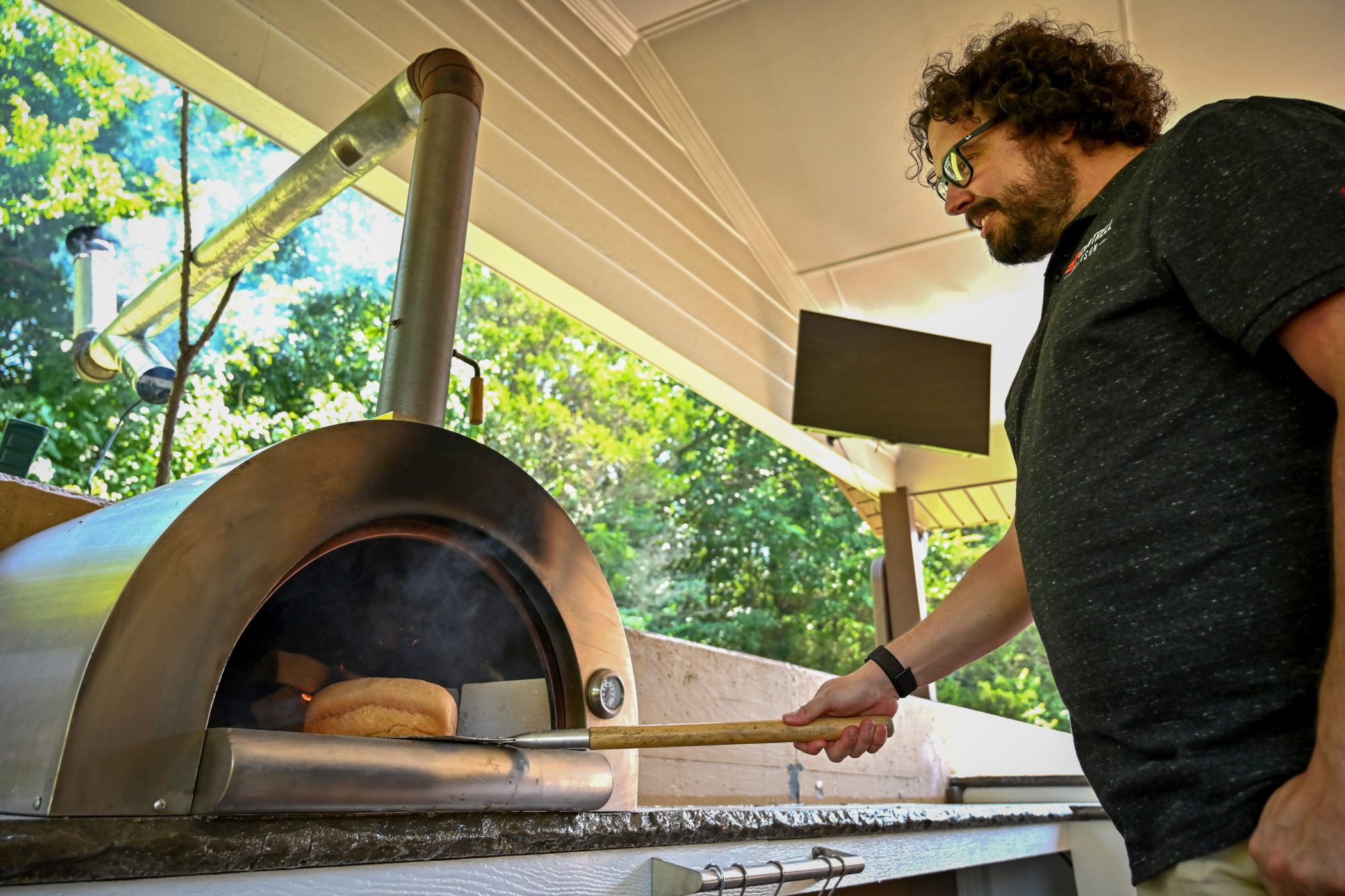 Jake Cantrell pulls a loaf of bread from his wood-fired outdoor oven