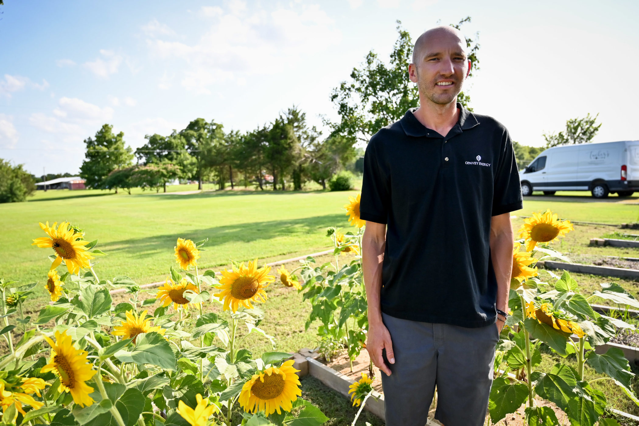 Cody Tucker stands between sunflower beds outside his home
