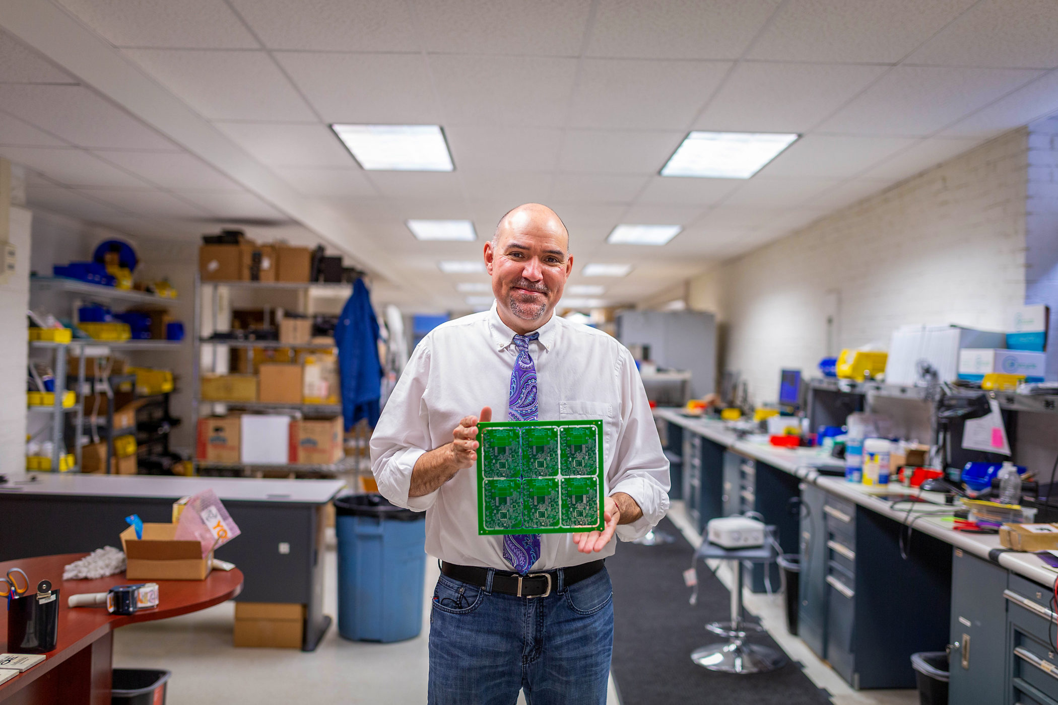 Paul Yost holds a circuit board in his company's workspace